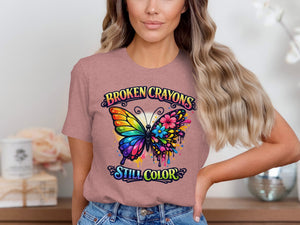 Woman wearing pink t-shirt with colorful butterfly graphic and text "Broken Crayons Still Color".