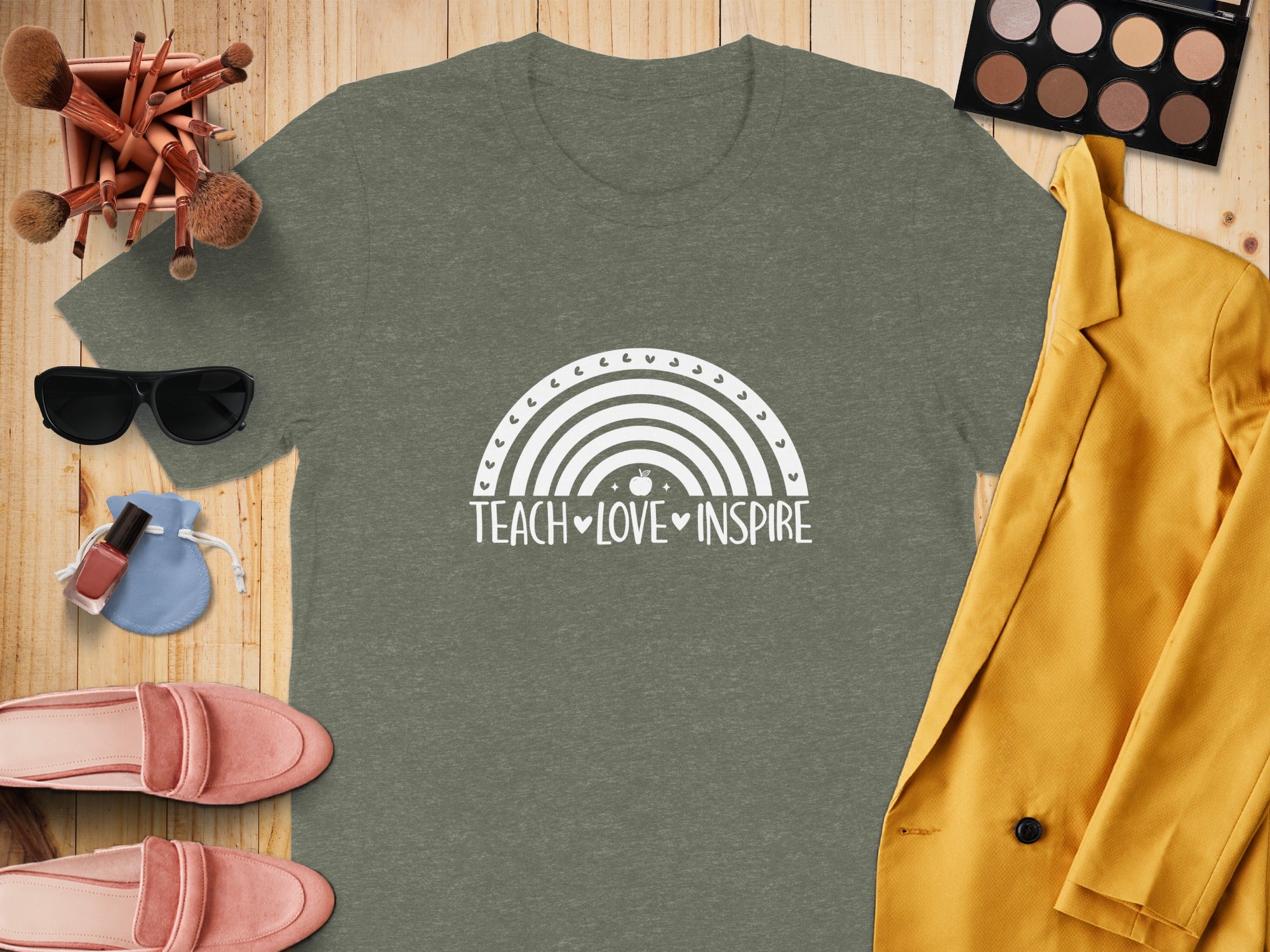 Green t-shirt with white text and rainbow graphic that says "TEACH ♡ LOVE ♡ INSPIRE."