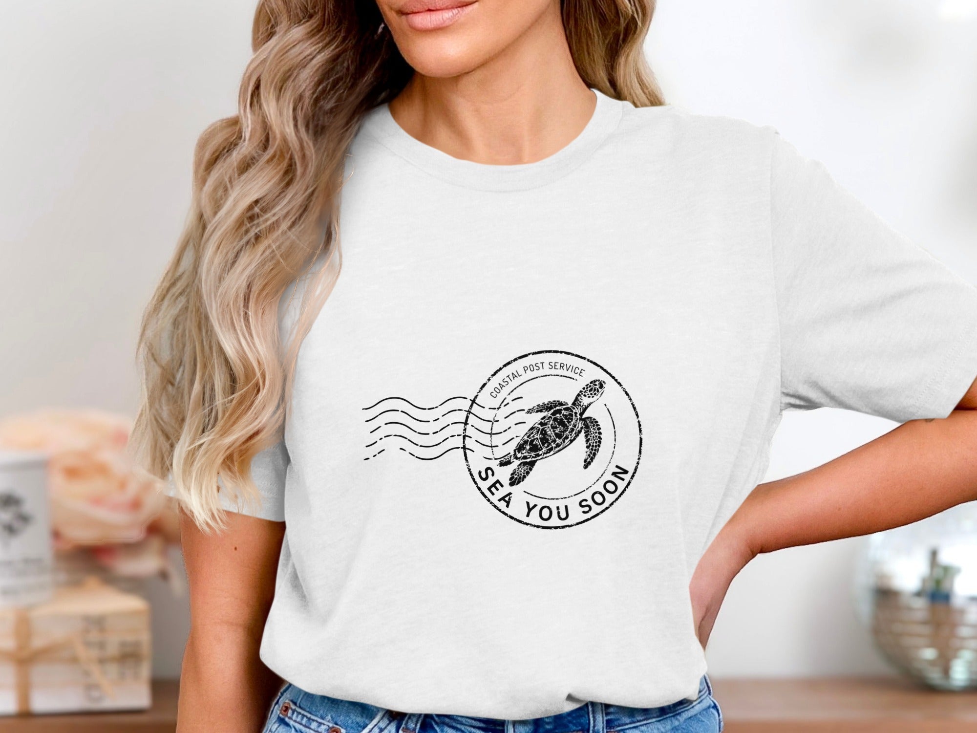 T-shirt with black circular stamp featuring a sea turtle and "SEA YOU SOON."