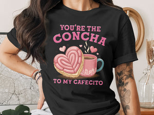 Black t-shirt with pink text "You're the Concha to my Cafecito" and heart-shaped concha.