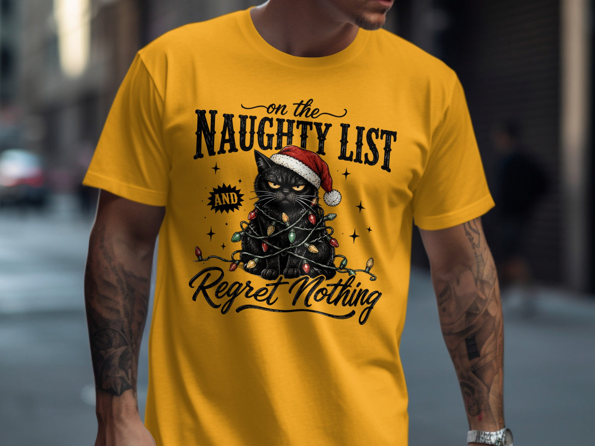 A person wearing a mustard yellow t-shirt featuring a graphic of a black cat tangled in Christmas lights with text reading On the Naughty List and Regret Nothing.