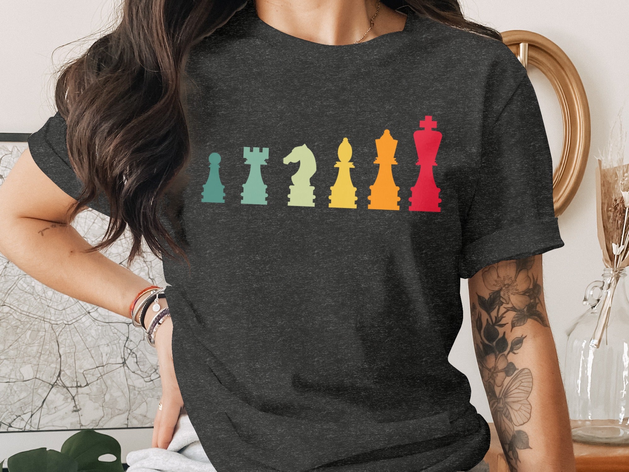 Drawn chess pieces in a colorful gradient from teal to red across a dark t-shirt.