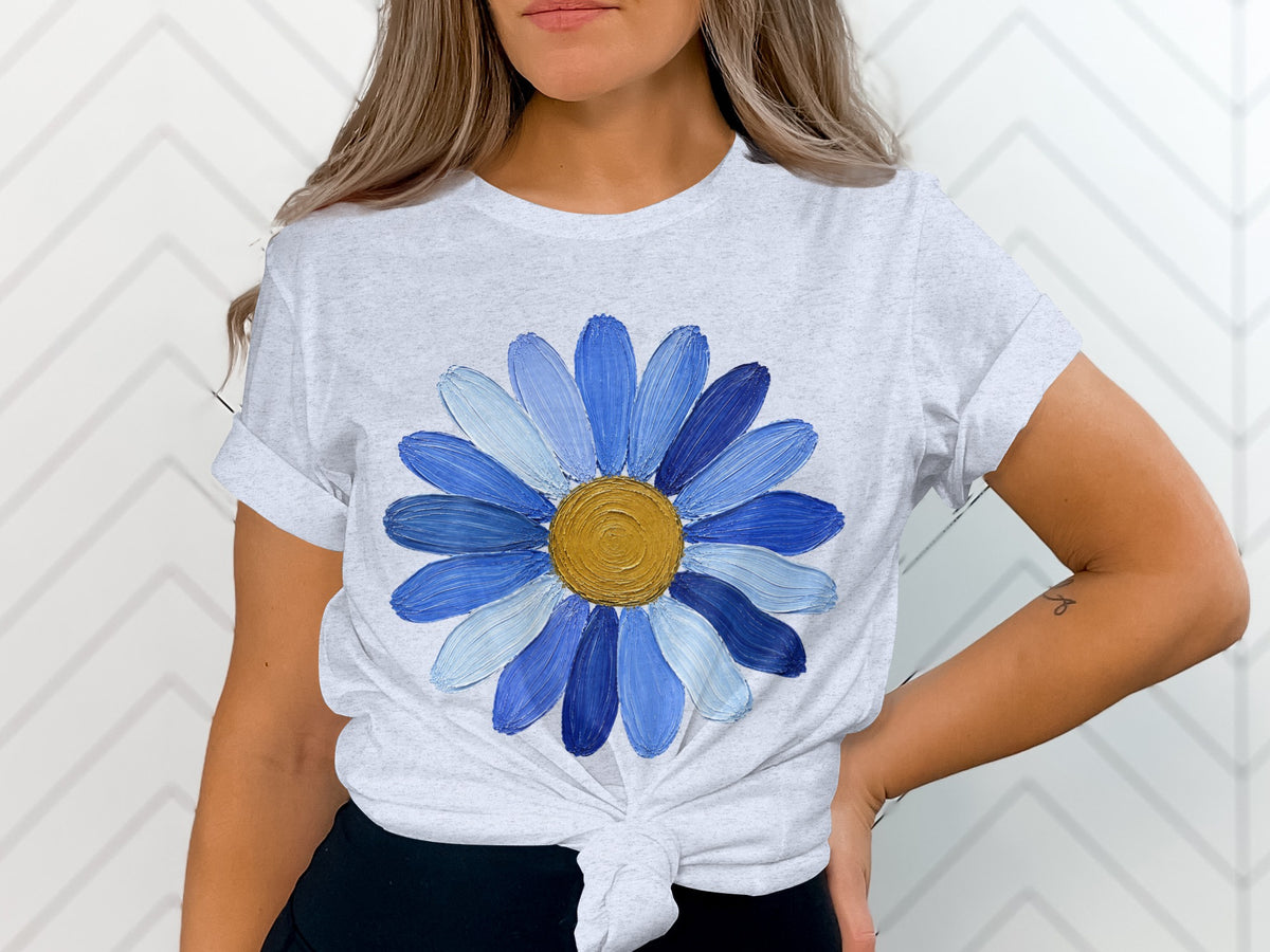 Gray t-shirt with a large, textured blue daisy graphic and a knotted hem.