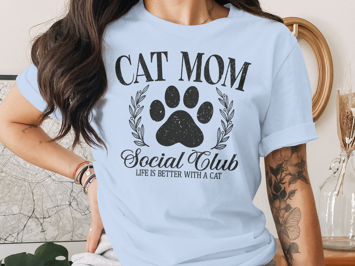 Light blue t-shirt with "CAT MOM Social Club LIFE IS BETTER WITH A CAT" text.