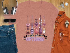 T-shirt with Halloween brooms, pumpkin, ghosts, bats, and text "A girl's gotta have OPTIONS!".