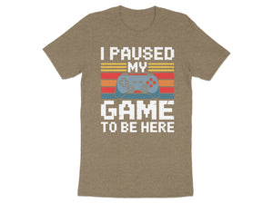 Brown t-shirt with "I paused my game to be here" and video game controller graphic.