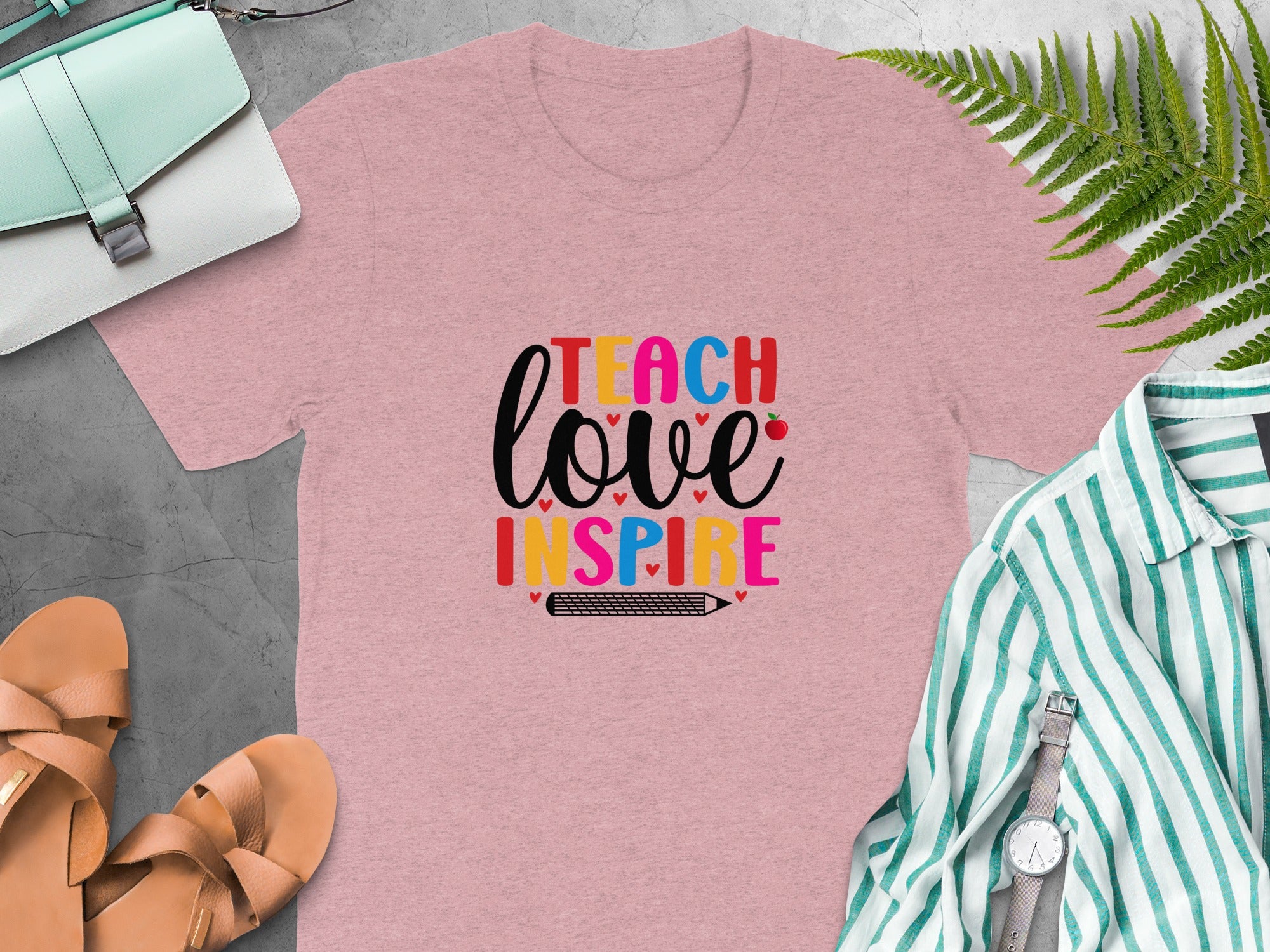Pink t-shirt with "Teach Love Inspire" text and a pencil graphic.