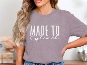 Lilac t-shirt with white text reading "MADE TO teach" and a heart.