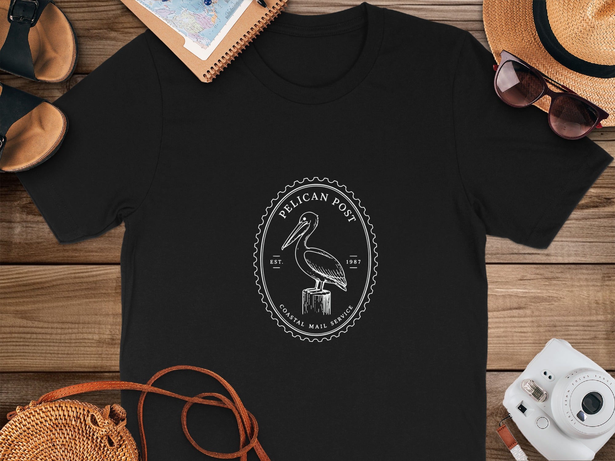 Black t-shirt with white pelican logo and text "Pelican Post Coastal Mail Service Est. 1987".