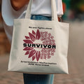 Tote bag with "Survivor" text, a sunflower graphic, and awareness ribbons.