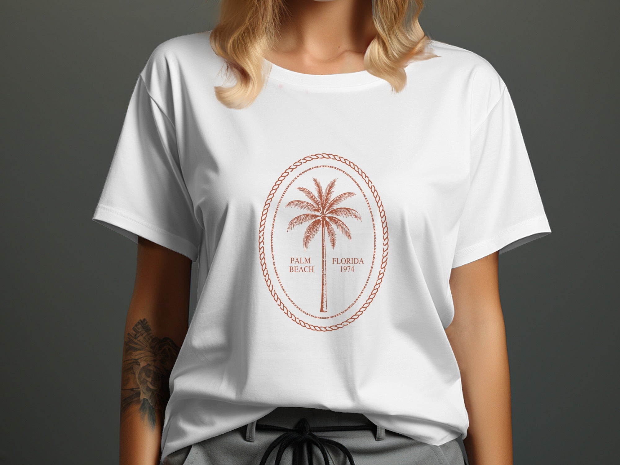 White t-shirt with a brown oval emblem featuring a palm tree, "Palm Beach," and "Florida 1974."