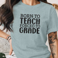 Light blue t-shirt with "BORN TO TEACH FORCED TO GRADE" text.