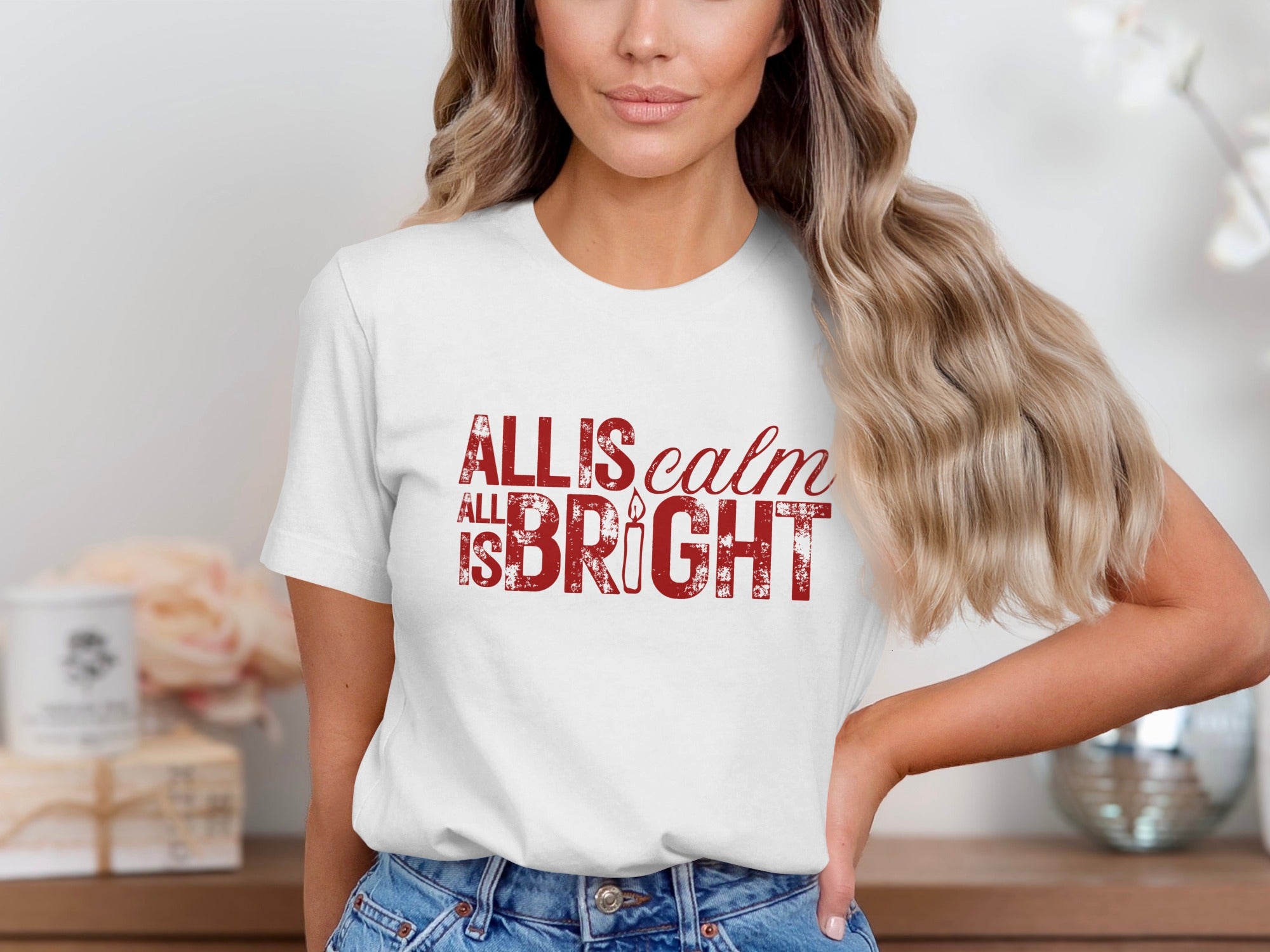 White t-shirt with red text reading "All is calm All is bright" with a candle graphic.