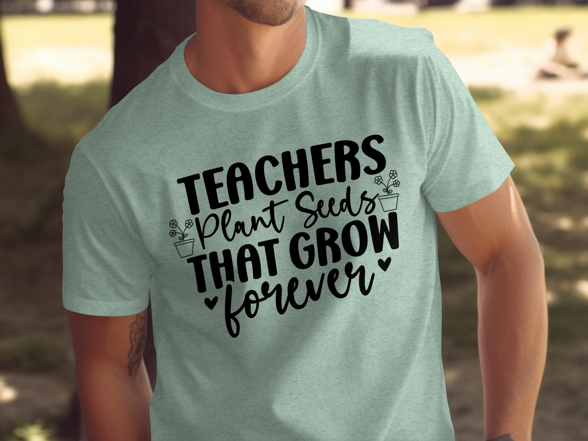 Light mint t-shirt with black text and floral graphics reading "TEACHERS Plant Seeds THAT GROW forever"