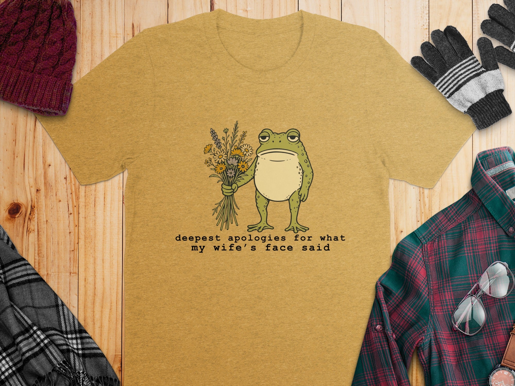 Yellow t-shirt with a cartoon frog holding flowers and text: deepest apologies for what my wife's face said.