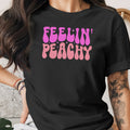 Black t-shirt with pink and light pink "Feelin' Peachy" text and sparkling stars.
