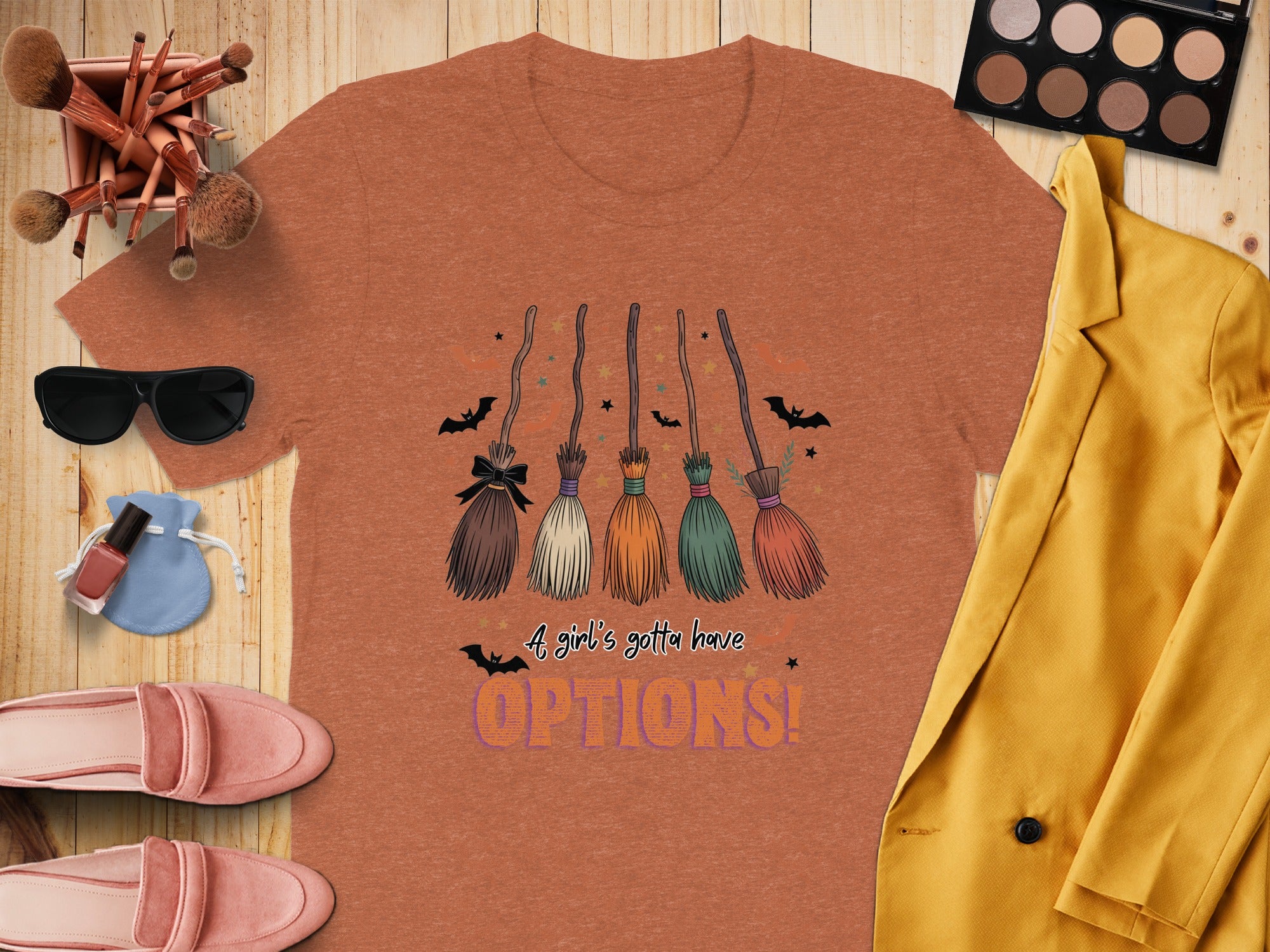 Orange t-shirt with Halloween graphic of witch brooms and text "OPTIONS!".