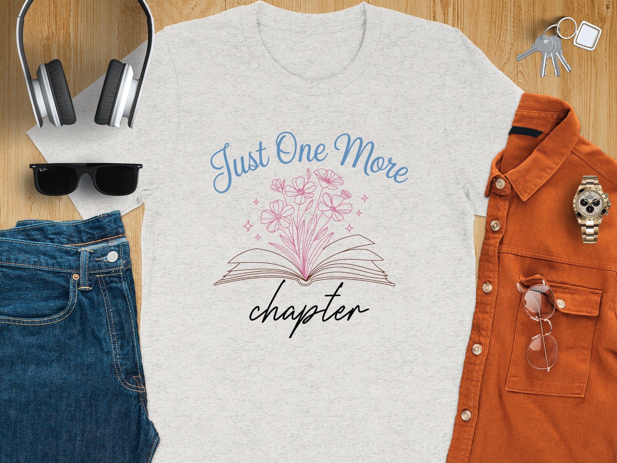 Light grey t-shirt with graphic of open book, flowers, and text "Just One More chapter".