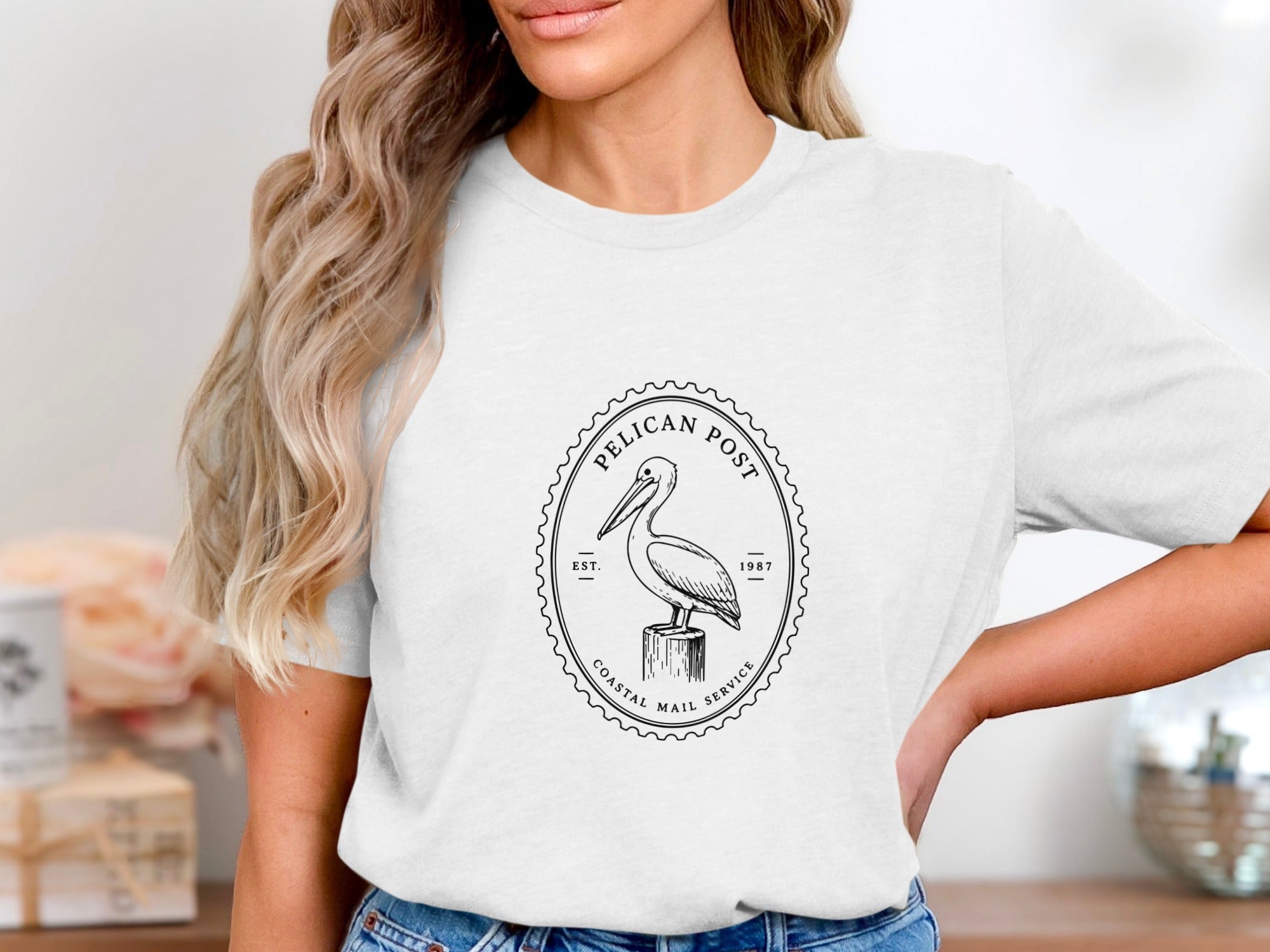 White t-shirt with a black oval stamp featuring a pelican on a post.