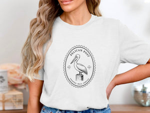 White t-shirt with a black oval stamp featuring a pelican on a post.