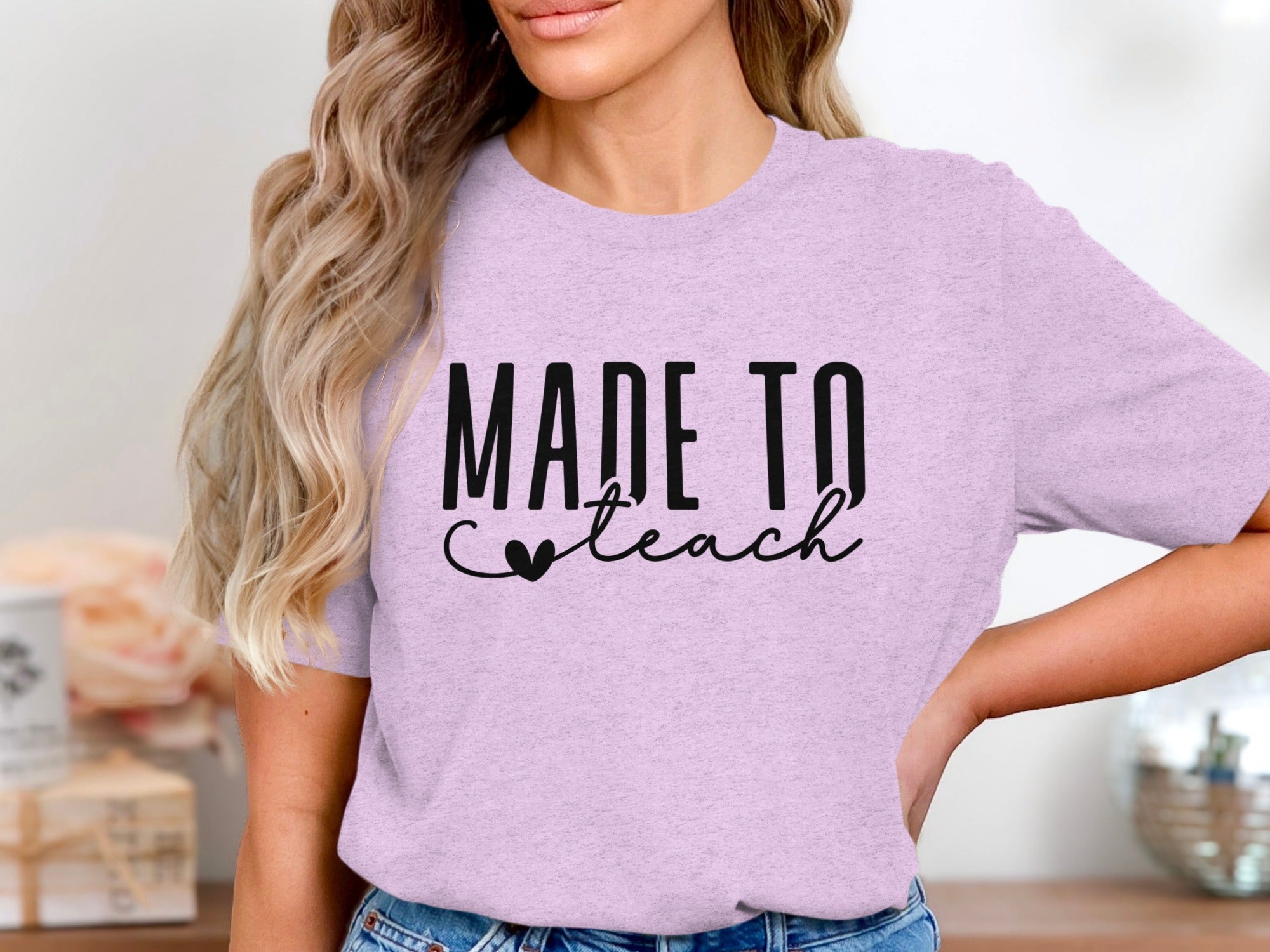 Lilac t-shirt with black text "MADE TO teach" and a heart.