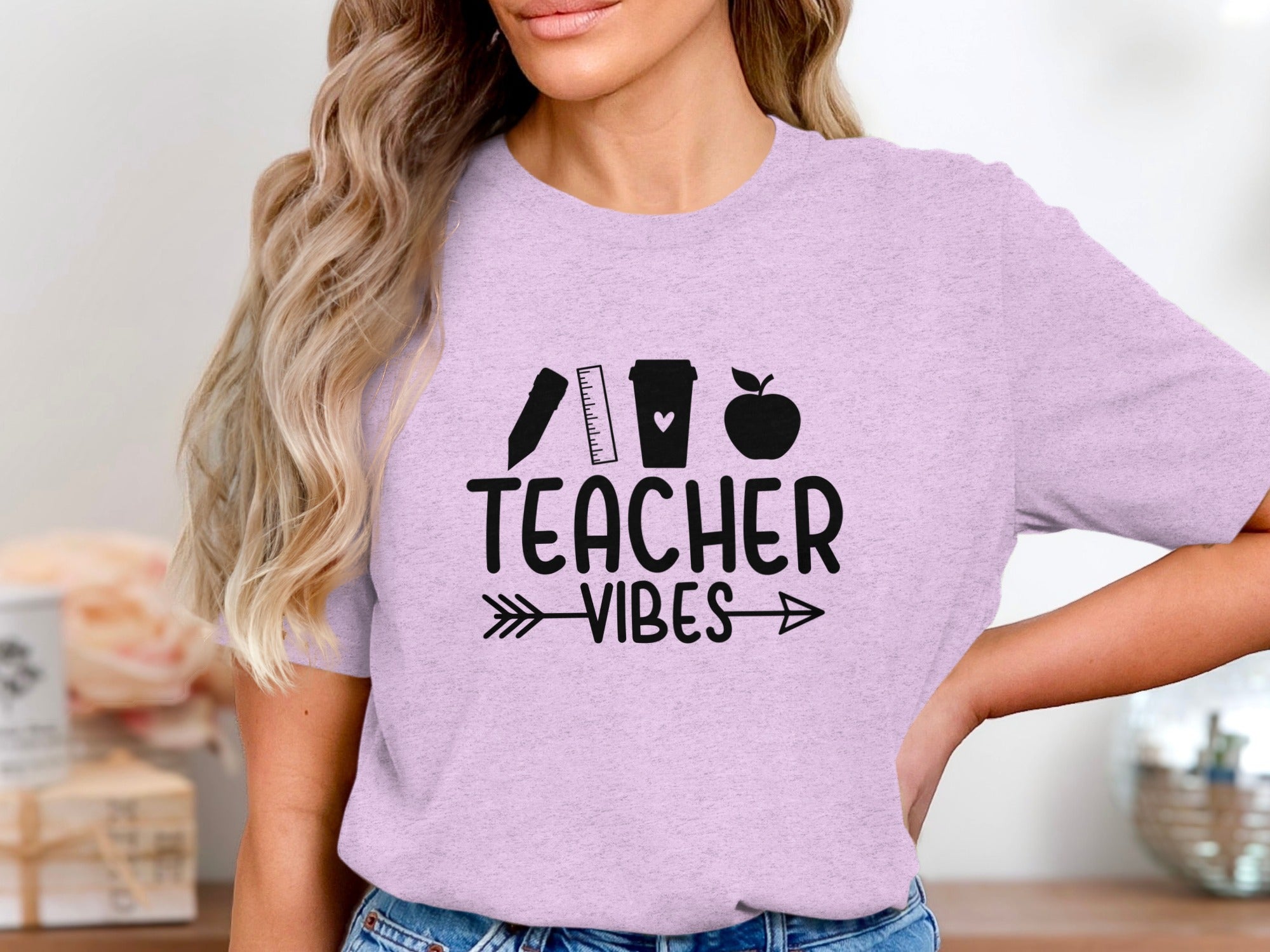 Lilac t-shirt with graphic of ruler, coffee cup, and apple above text "TEACHER VIBES".