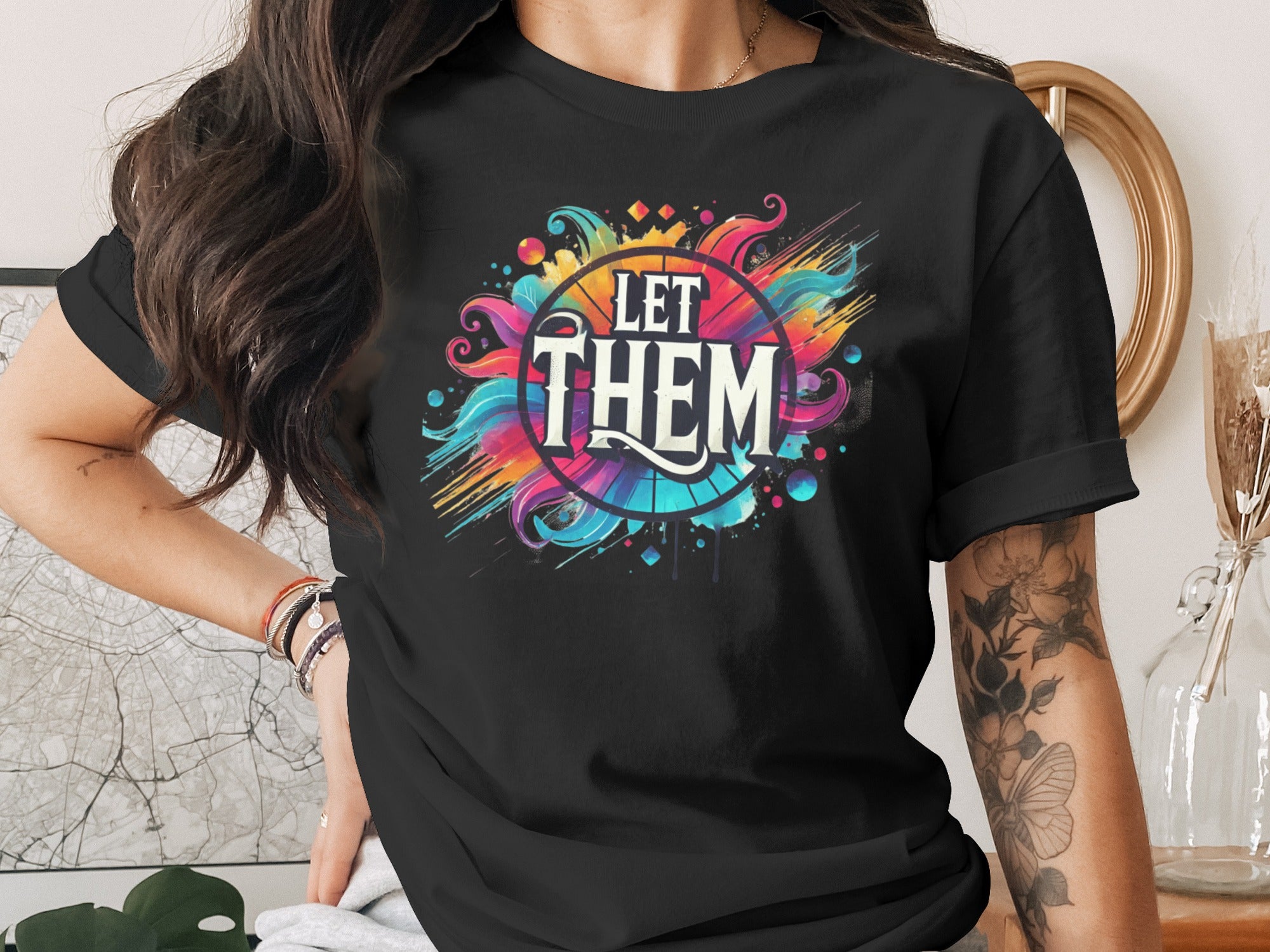 Black t-shirt with vibrant "LET THEM" graphic design and watercolor splashes.