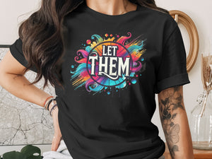 Black t-shirt with vibrant "LET THEM" graphic design and watercolor splashes.