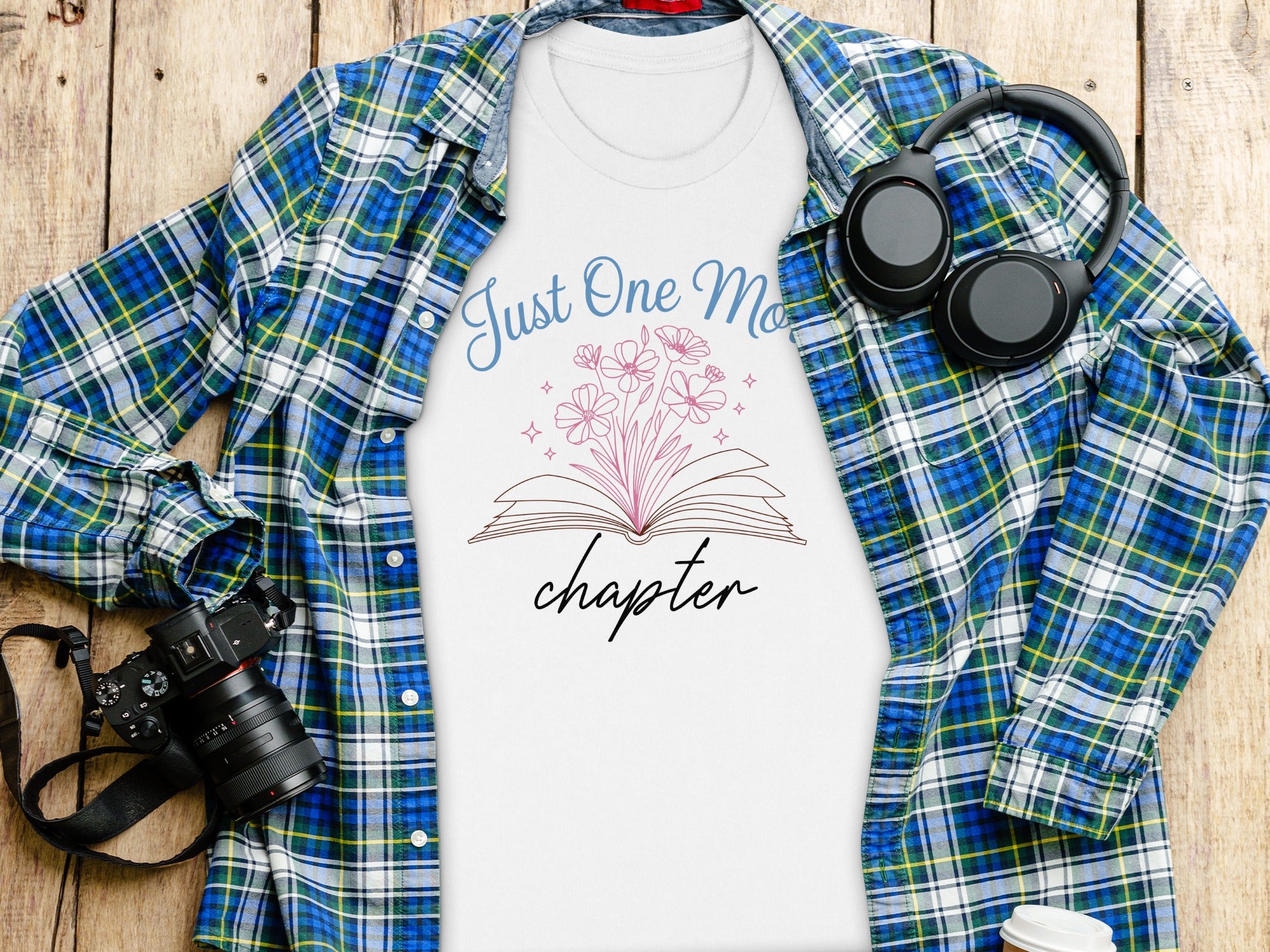 White t-shirt with blue text "Just One More Chapter" and pink floral design.