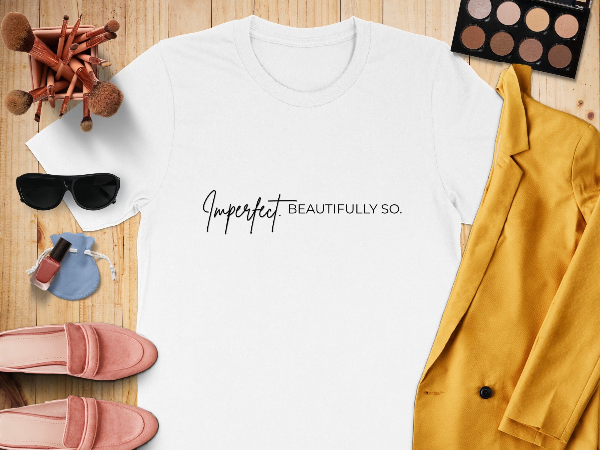 White t-shirt with "Imperfect BEAUTIFULLY SO." text, makeup, sunglasses, and fashion items.