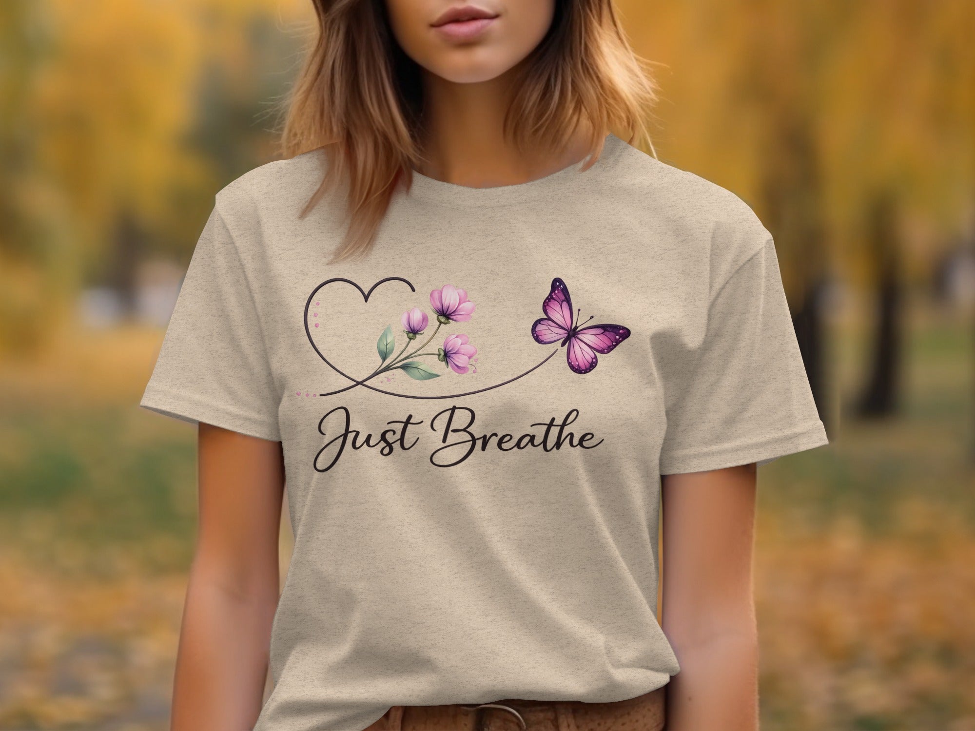 Light beige t-shirt with black script text "Just Breathe" and butterfly floral design.