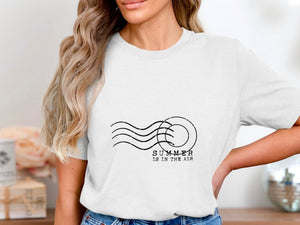 White t-shirt with "SUMMER IS IN THE AIR" text and wavy lines graphic.