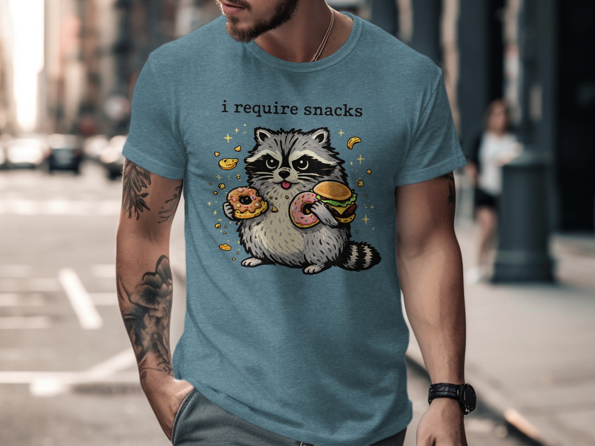 T-shirt with cartoon raccoon holding a burger and donuts, text "i require snacks."