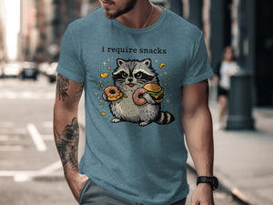 T-shirt with cartoon raccoon holding a burger and donuts, text "i require snacks."