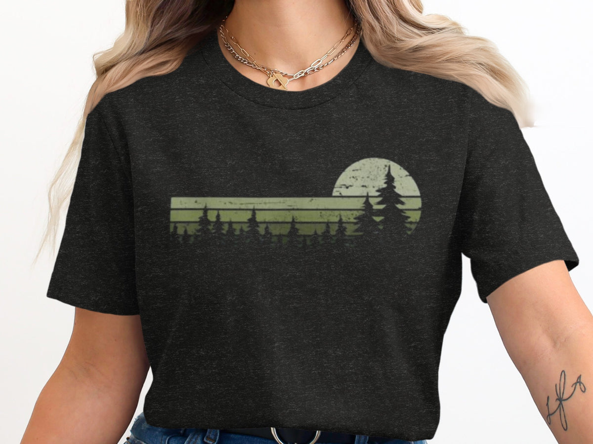 Dark t-shirt with a distressed graphic of pine trees against a muted sunset circle.