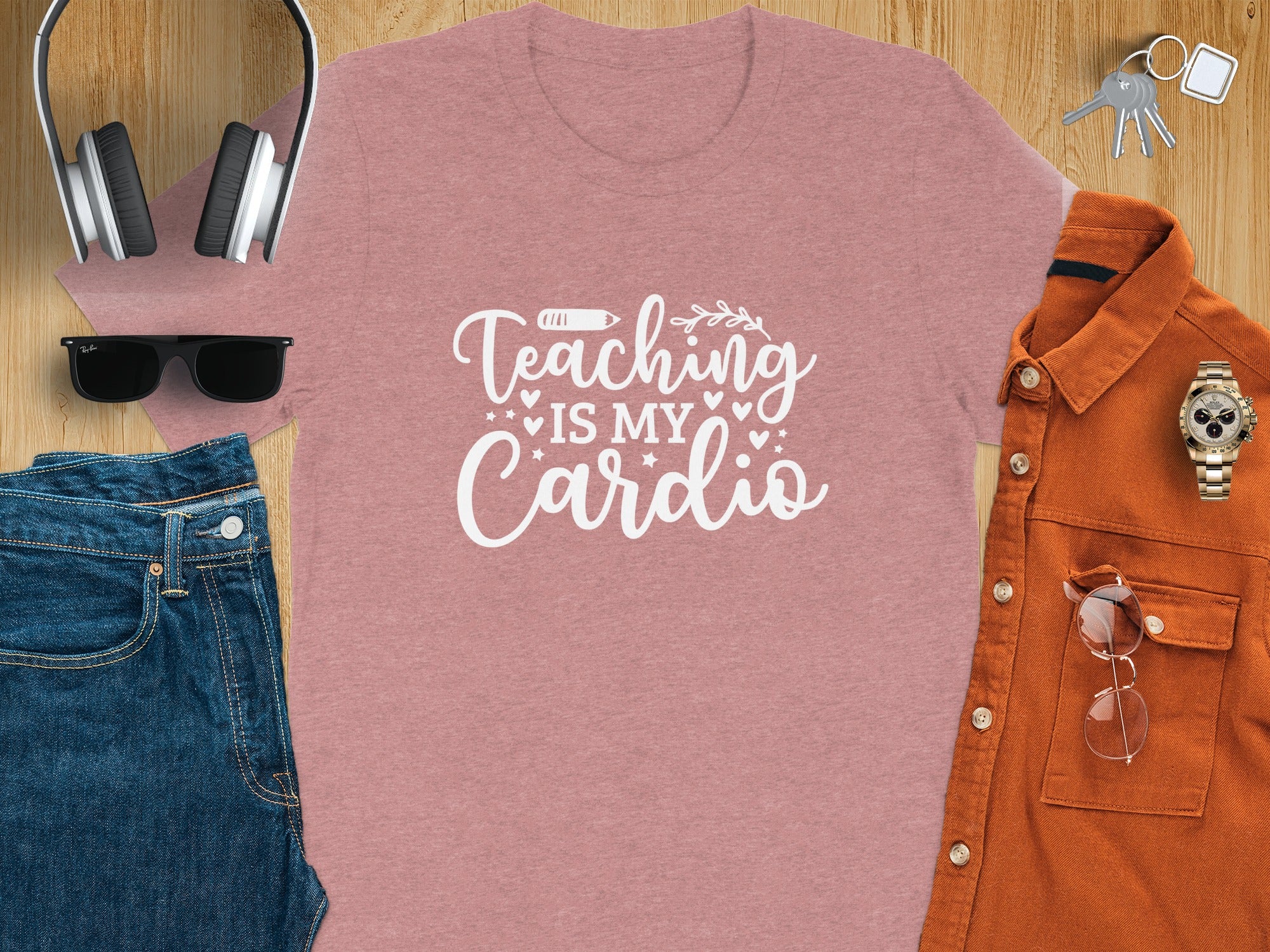 Pink t-shirt with "Teaching Is My Cardio" text, displayed with jeans, headphones, and keys.