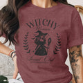 Maroon t-shirt with "Witchy Woman Social Club" graphic and witch illustration.