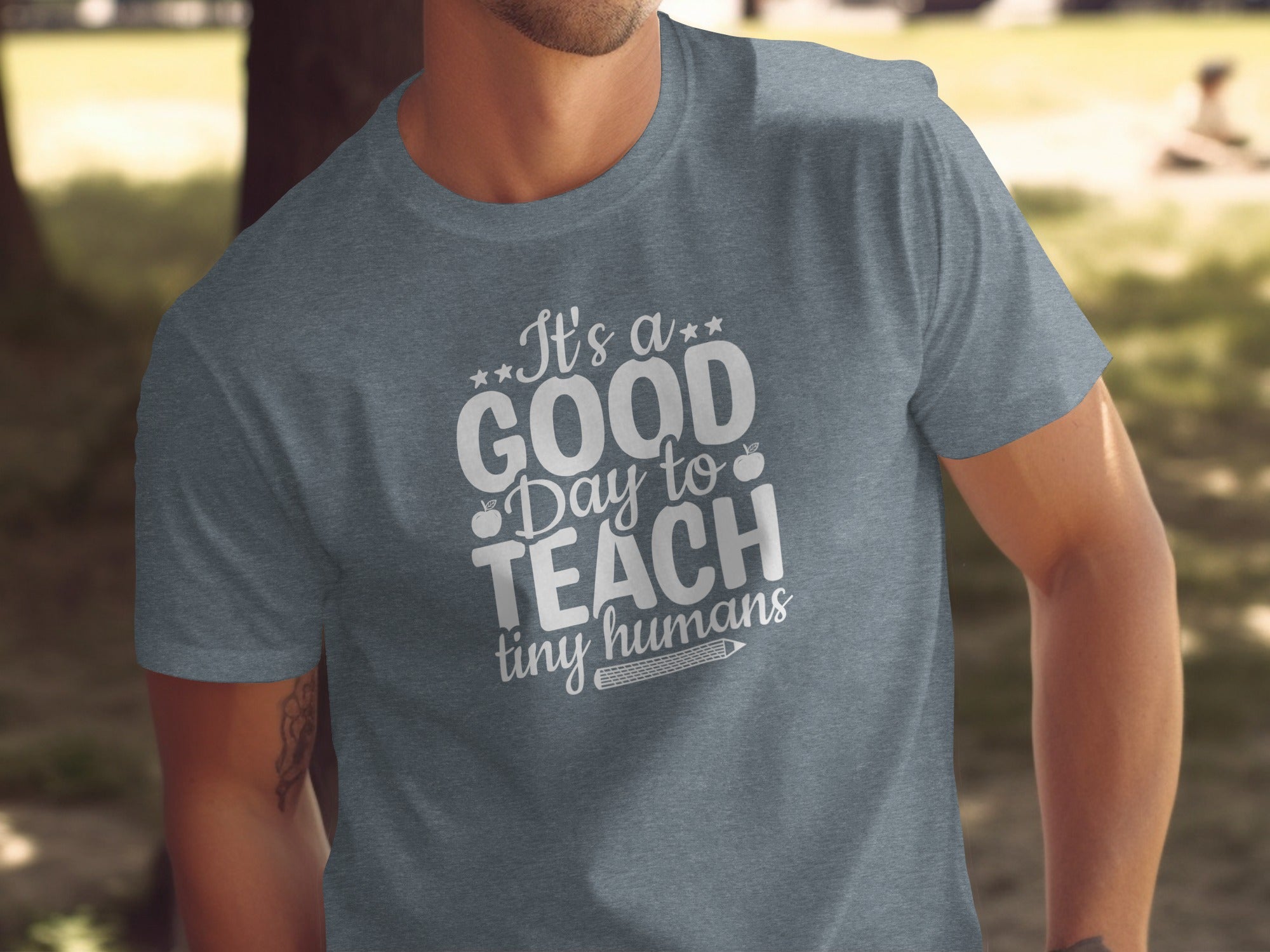 T-shirt with white text: "It's a GOOD Day to TEACH tiny humans" and apple icon.