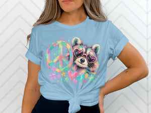 Light blue t-shirt with a watercolor-style raccoon wearing heart sunglasses and a peace sign.
