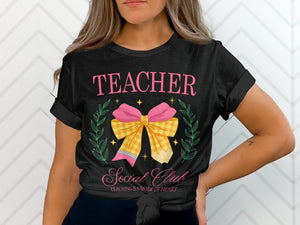 Black t-shirt with pink text "TEACHER Social Club" and a pencil-bow graphic.