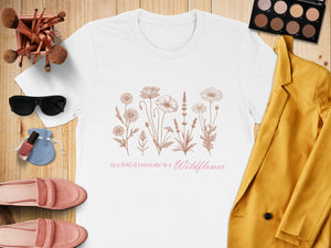 White t-shirt with floral design and text "in a field of roses she is a Wildflower."