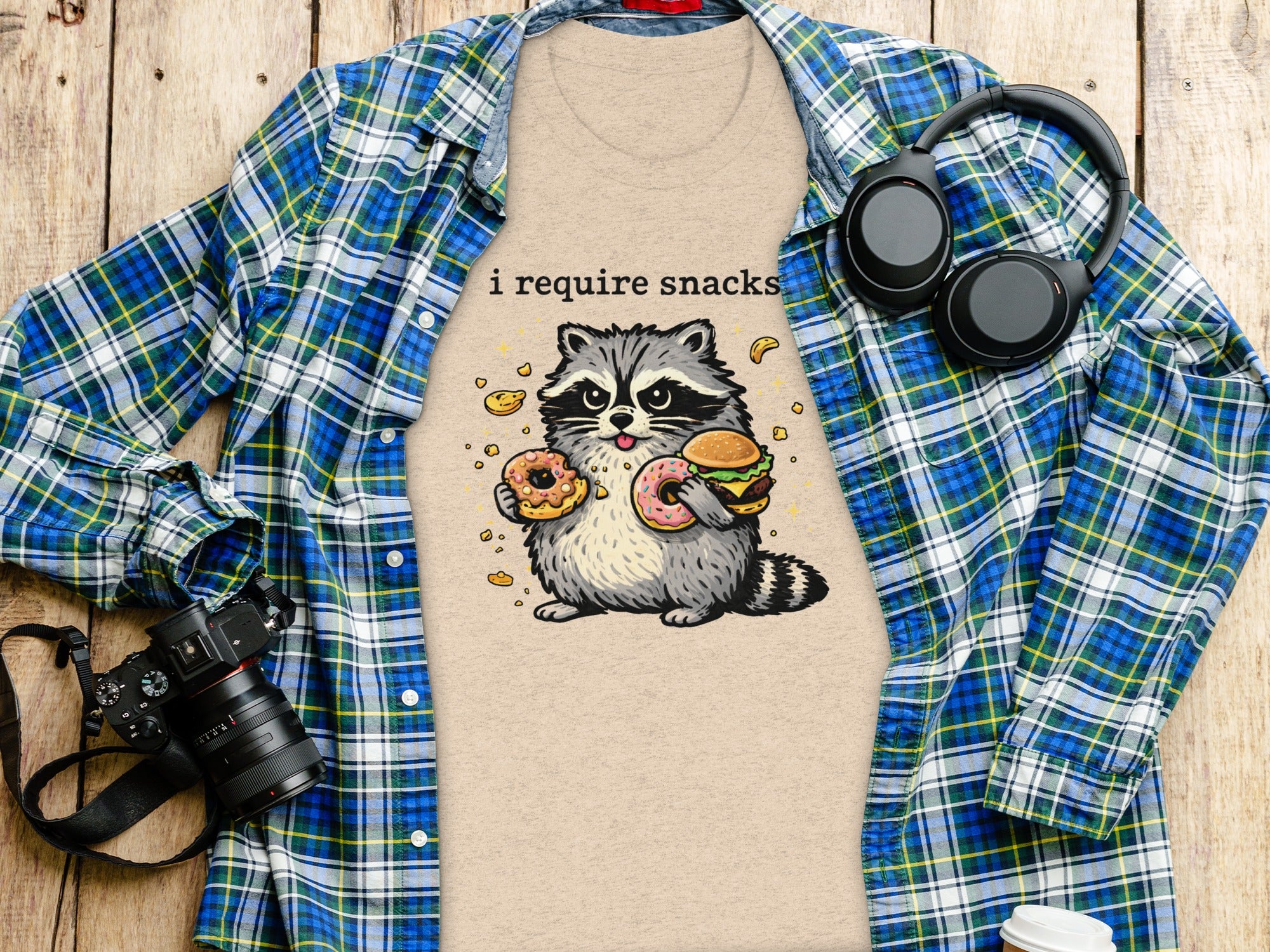T-shirt with graphic of raccoon holding donuts and a burger with text "i require snacks".