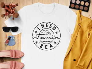 White t-shirt with "I NEED vitamin SEA" graphic and beach theme accessories.