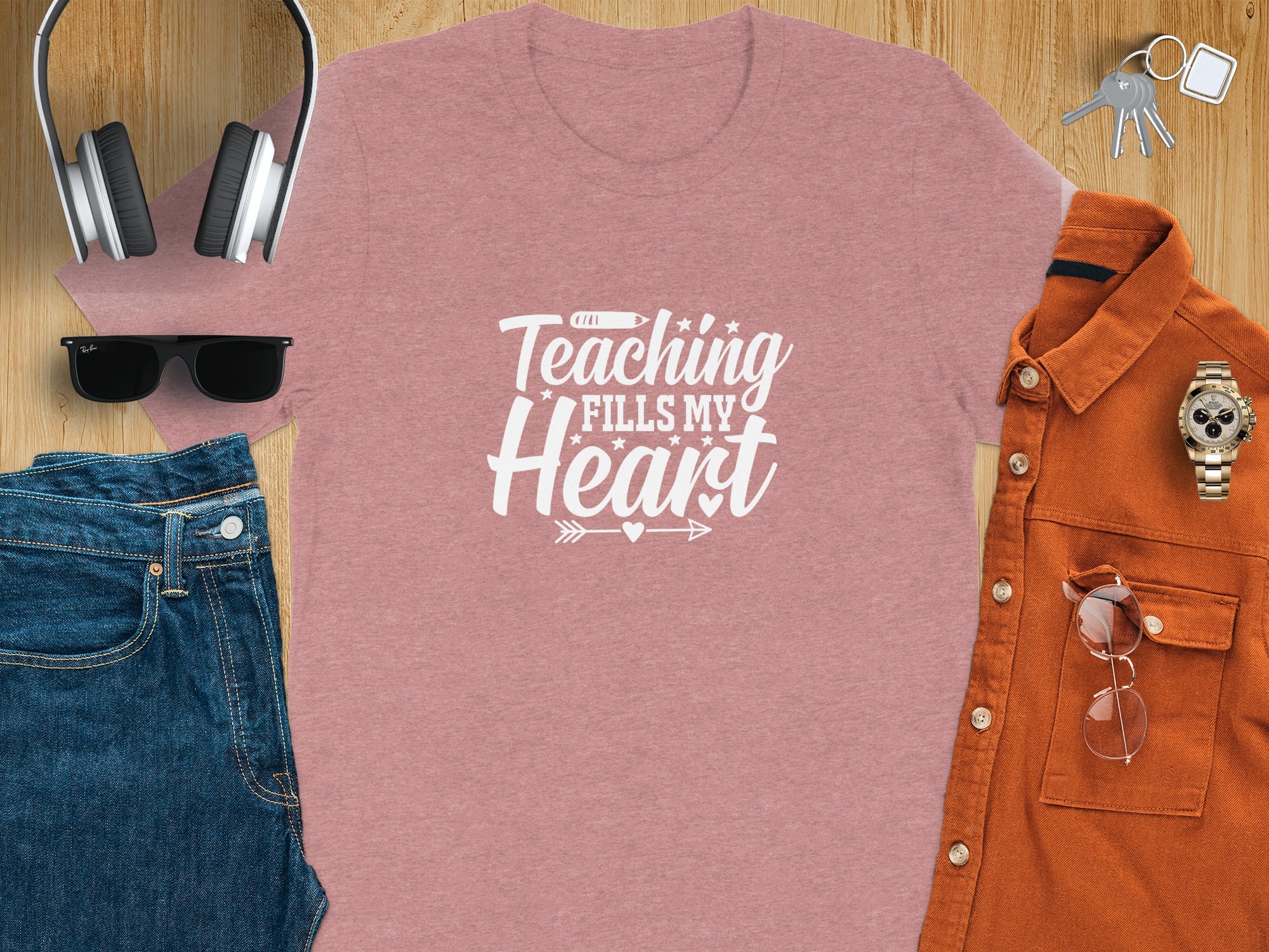 Pink t-shirt with white text "Teaching Fills My Heart" among other items.