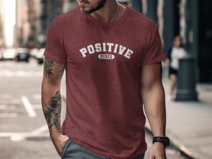 Maroon t-shirt with white "POSITIVE VIBES" text on chest, worn by a man with tattoos.