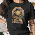 Black t-shirt with "Radiate Positivity" graphic featuring a sun, rainbow, plants, and cacti.