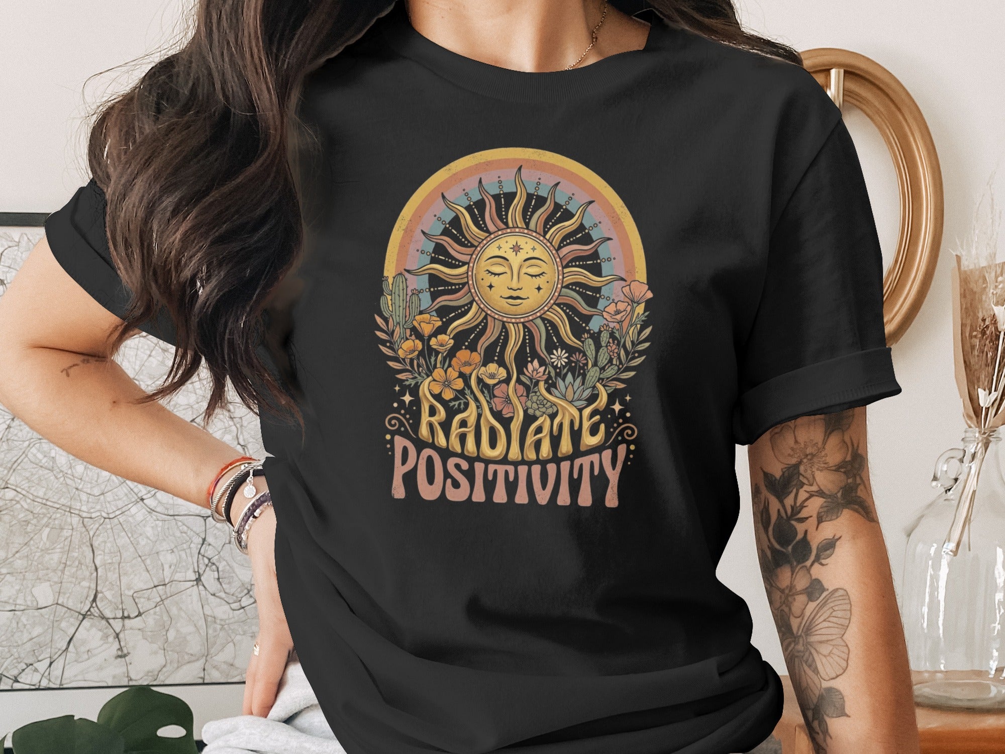 Black t-shirt with "Radiate Positivity" graphic featuring a sun, rainbow, plants, and cacti.