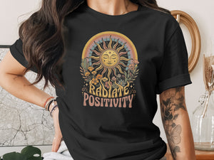 Black t-shirt with "Radiate Positivity" graphic featuring a sun, rainbow, plants, and cacti.