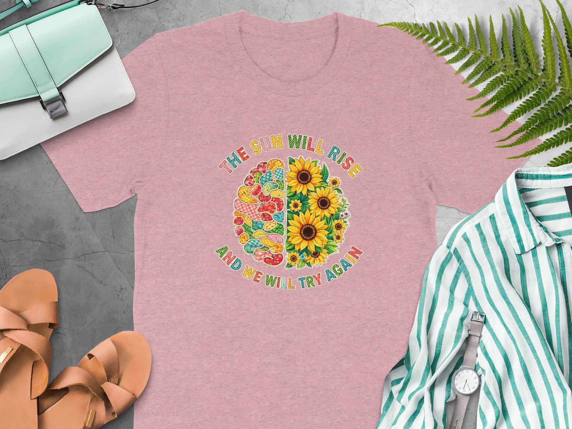 Pink t-shirt with circular graphic featuring sunflowers and a patchwork brain, saying text.