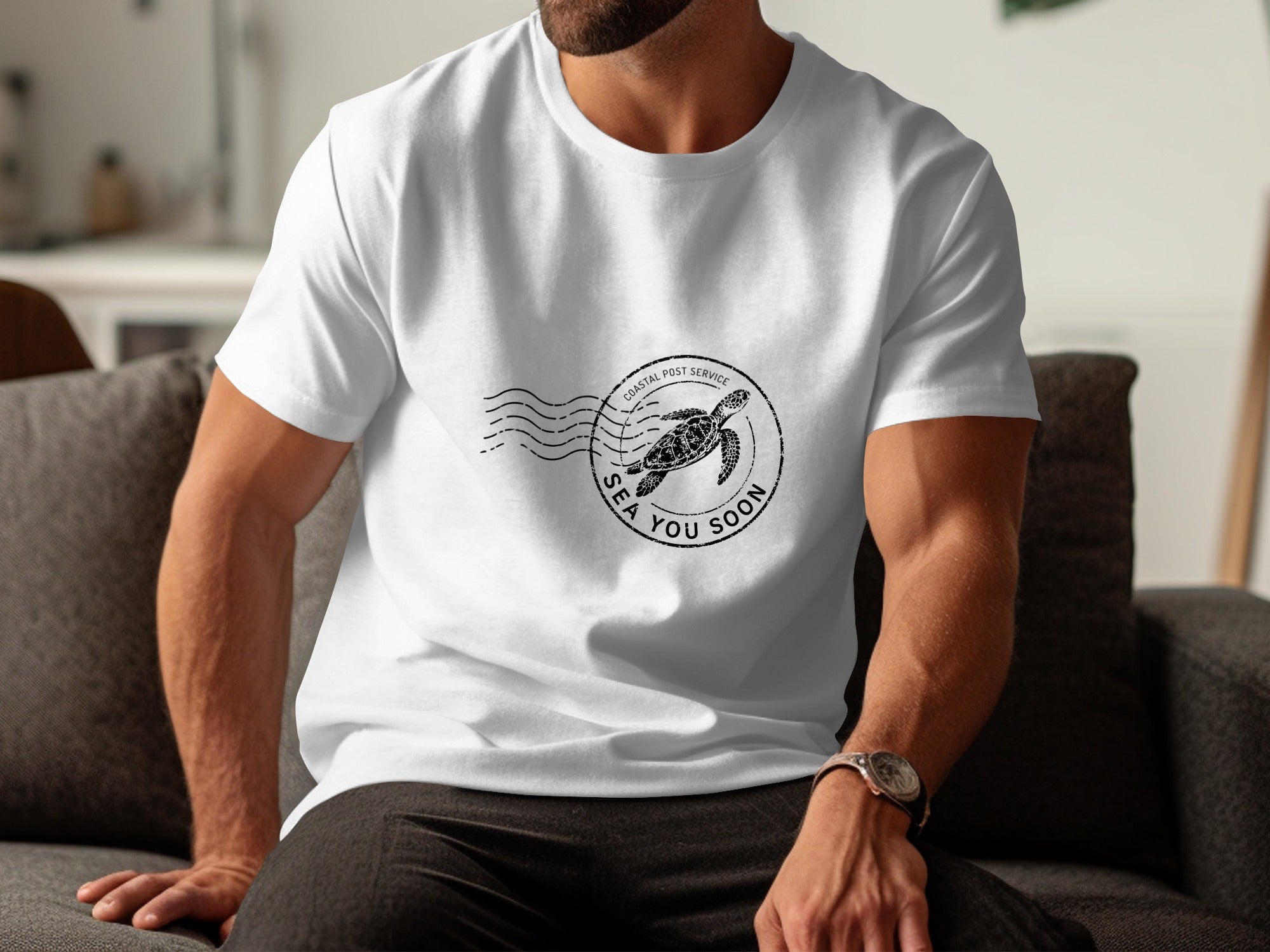 White t-shirt with a black circular stamp featuring a sea turtle and "Coastal Post Service Sea You Soon."